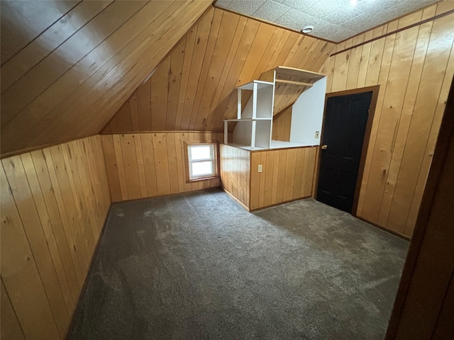 bonus room with lofted ceiling, wooden walls, and dark colored carpet