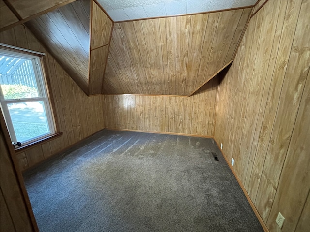 additional living space with lofted ceiling, wooden walls, dark colored carpet, and wood ceiling