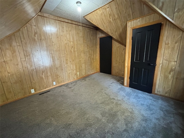 additional living space with lofted ceiling, wood walls, and carpet