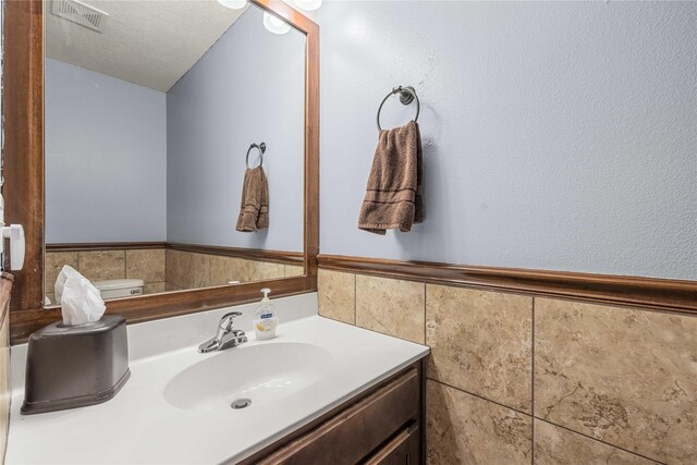 bathroom featuring vanity, a textured ceiling, and toilet