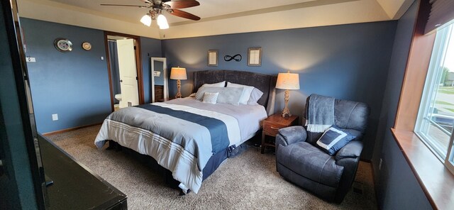 bedroom with carpet flooring, connected bathroom, a raised ceiling, and ceiling fan