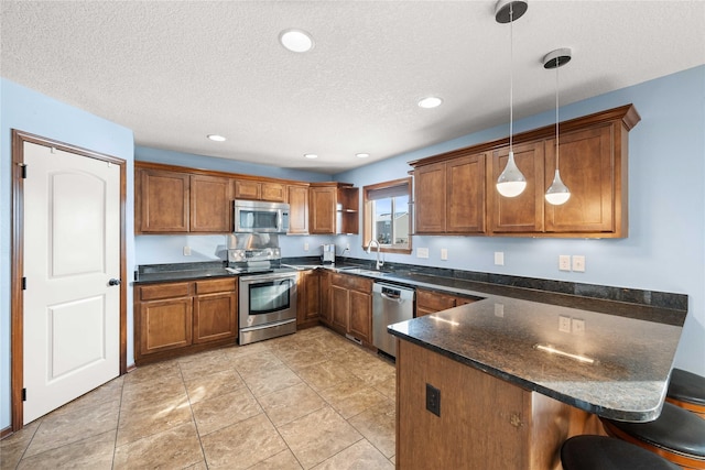 kitchen featuring a breakfast bar, sink, hanging light fixtures, appliances with stainless steel finishes, and kitchen peninsula