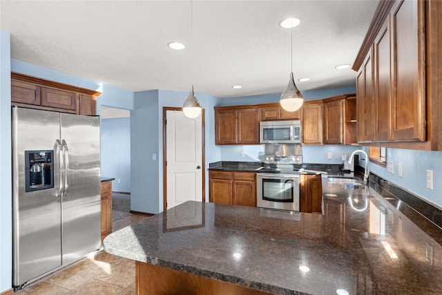 kitchen featuring sink, hanging light fixtures, stainless steel appliances, kitchen peninsula, and dark stone counters