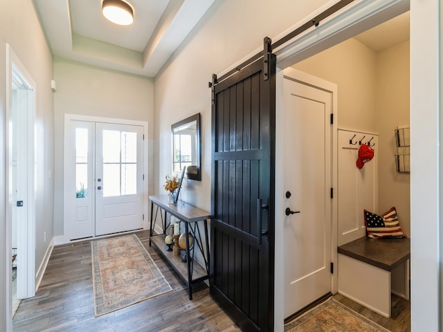 mudroom featuring a barn door, dark hardwood / wood-style floors, and a raised ceiling