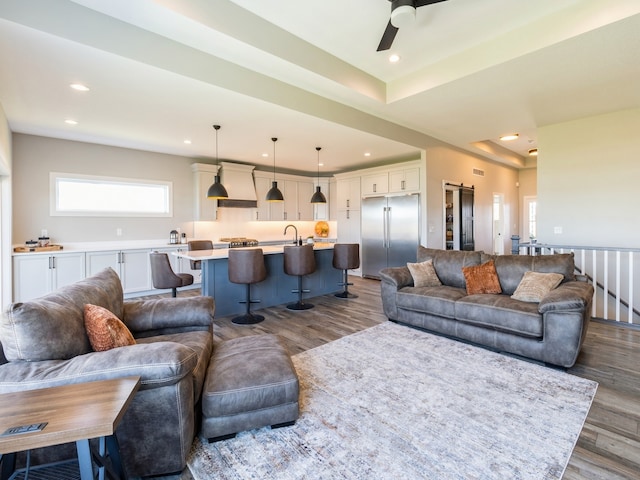 living room featuring ceiling fan, sink, and hardwood / wood-style floors