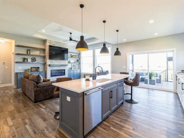 kitchen featuring a brick fireplace, sink, a wealth of natural light, ceiling fan, and stainless steel dishwasher