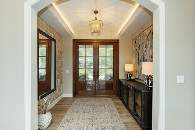 interior space with light wood-type flooring, a tray ceiling, plenty of natural light, and a notable chandelier