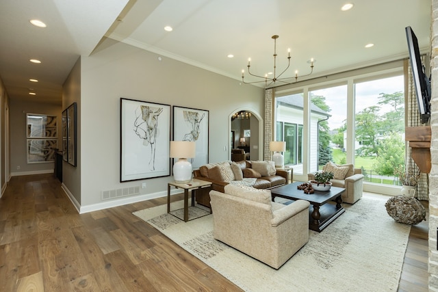 living room featuring ornamental molding, wood-type flooring, and a chandelier