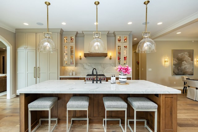 kitchen with decorative light fixtures, light stone countertops, a spacious island, and light hardwood / wood-style flooring