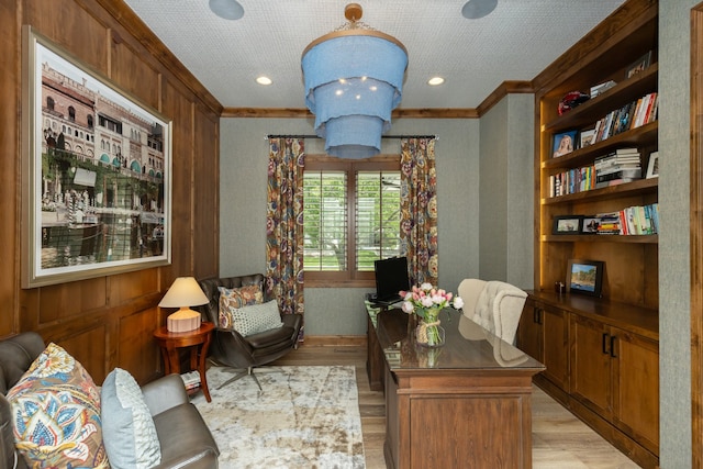 office area with light wood-type flooring, wood walls, and crown molding