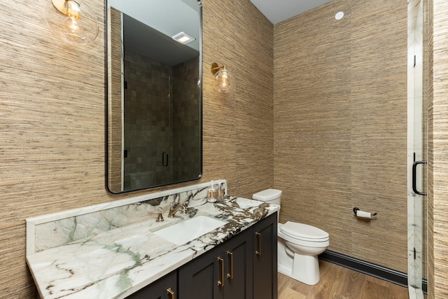 bathroom with vanity, toilet, hardwood / wood-style flooring, and a shower with door