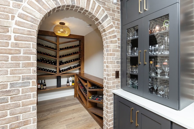 wine area with brick wall and hardwood / wood-style flooring