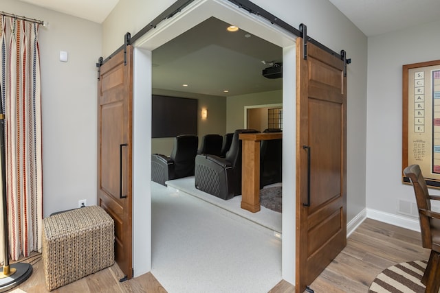 hallway with a barn door and hardwood / wood-style floors