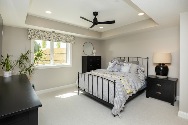 bedroom featuring a raised ceiling, ceiling fan, and carpet flooring