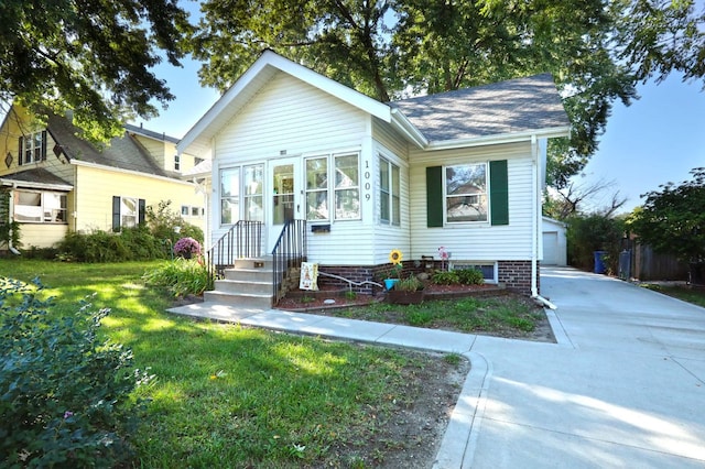 bungalow featuring a garage, an outdoor structure, and a front lawn