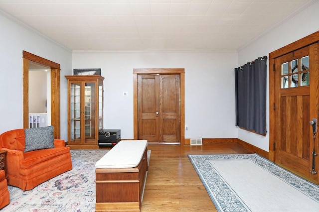 foyer entrance featuring light hardwood / wood-style floors and crown molding