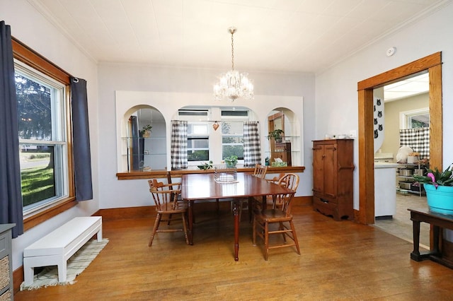 dining room with a healthy amount of sunlight, ornamental molding, light hardwood / wood-style flooring, and a chandelier