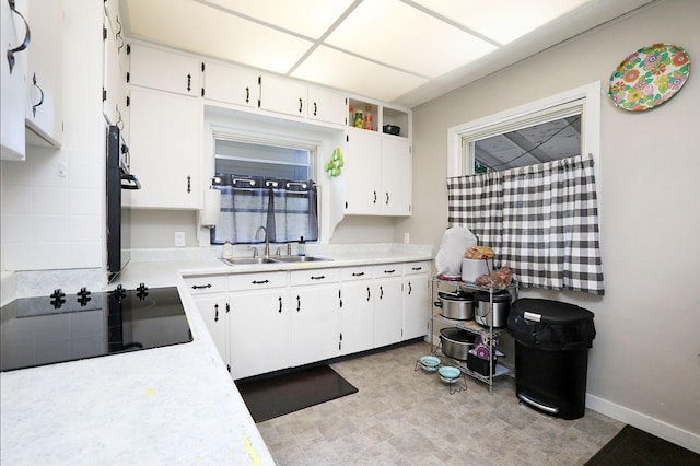 kitchen featuring wall oven, black electric cooktop, white cabinetry, and sink