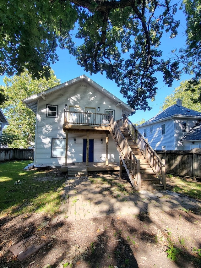 rear view of property featuring a wooden deck and a lawn