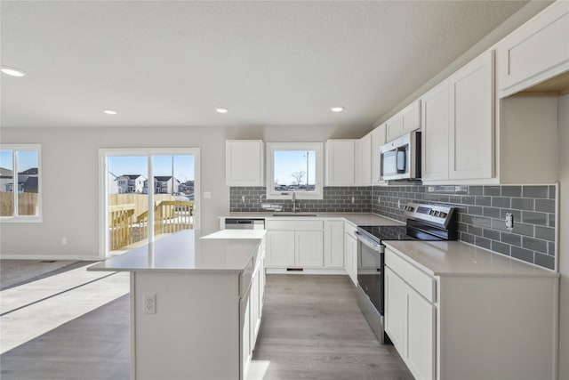 kitchen with decorative backsplash, a kitchen island, white cabinetry, appliances with stainless steel finishes, and sink