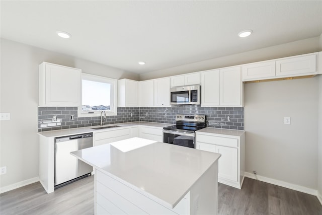 kitchen featuring stainless steel appliances, a kitchen island, white cabinets, and sink