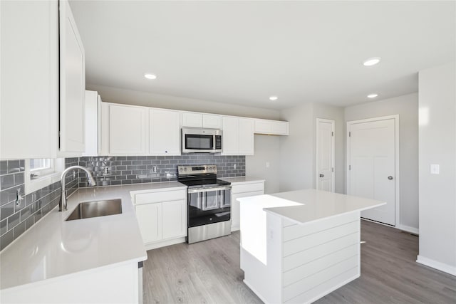 kitchen featuring sink, stainless steel appliances, white cabinets, and a center island