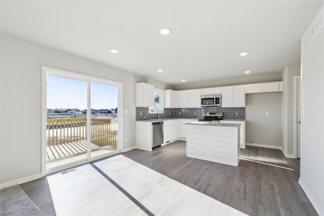 kitchen featuring a kitchen island, white cabinets, appliances with stainless steel finishes, and dark hardwood / wood-style floors