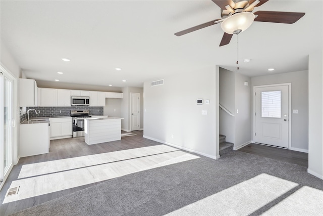 kitchen featuring stainless steel appliances, sink, white cabinetry, ceiling fan, and a kitchen island