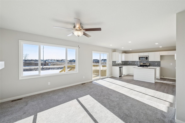 unfurnished living room with ceiling fan, carpet, and sink