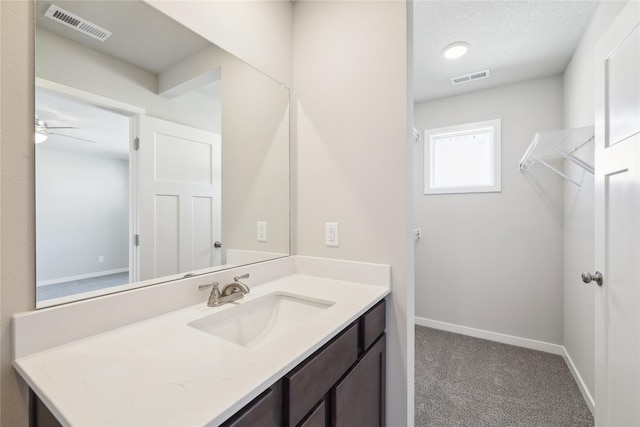 bathroom with a textured ceiling, ceiling fan, and vanity