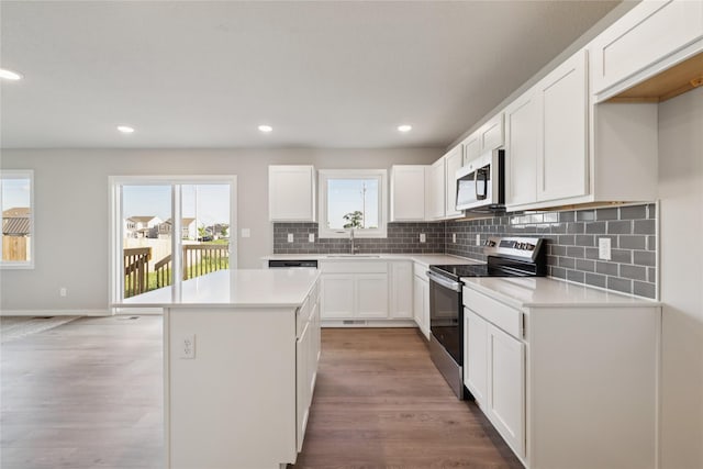 805 3rd St NW, Bondurant, IA 50035 - kitchen with appliances with stainless steel finishes, a kitchen island, tasteful backsplash, light wood finished floors, and light countertops