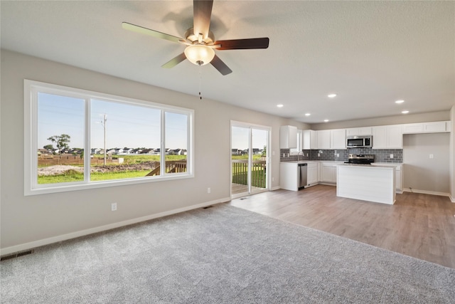 805 3rd St NW, Bondurant, IA 50035 - kitchen featuring stainless steel appliances, open floor plan, white cabinets, backsplash, and recessed lighting