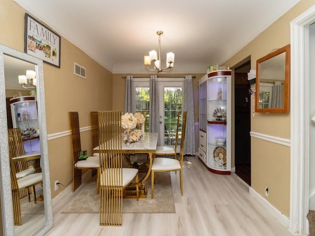 dining room featuring light hardwood / wood-style floors, french doors, and an inviting chandelier