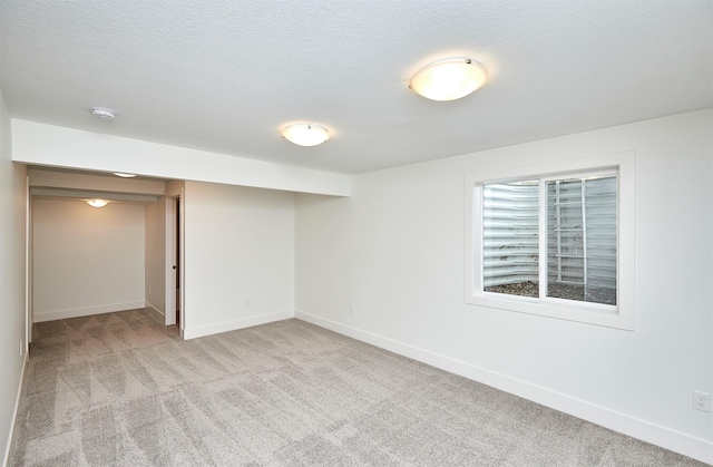 basement featuring light colored carpet and a textured ceiling