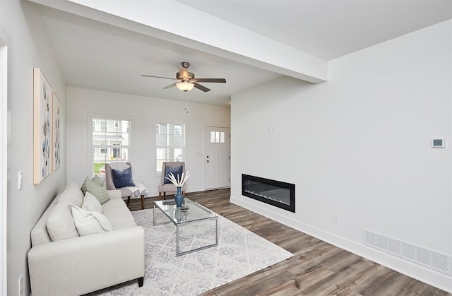 living room featuring beamed ceiling, dark hardwood / wood-style floors, and ceiling fan