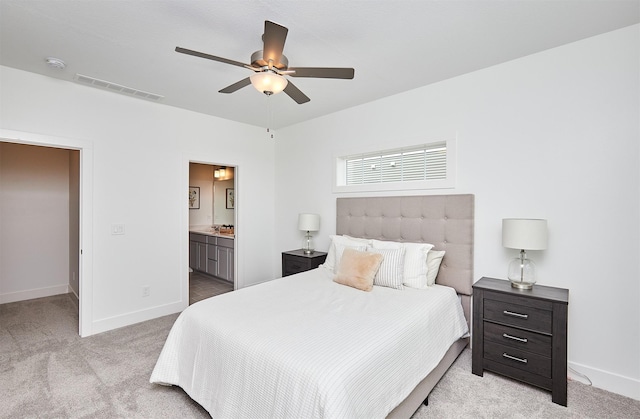 bedroom featuring light carpet, ensuite bathroom, and ceiling fan