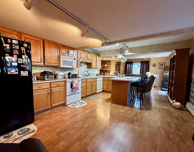 kitchen featuring light hardwood / wood-style floors, a kitchen bar, white appliances, and a textured ceiling