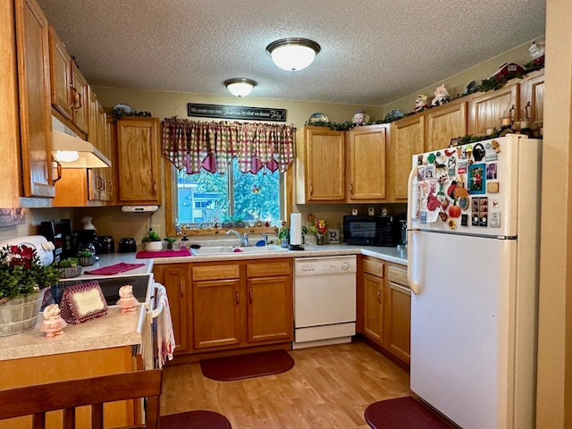 kitchen with a textured ceiling, light wood-type flooring, white appliances, and sink