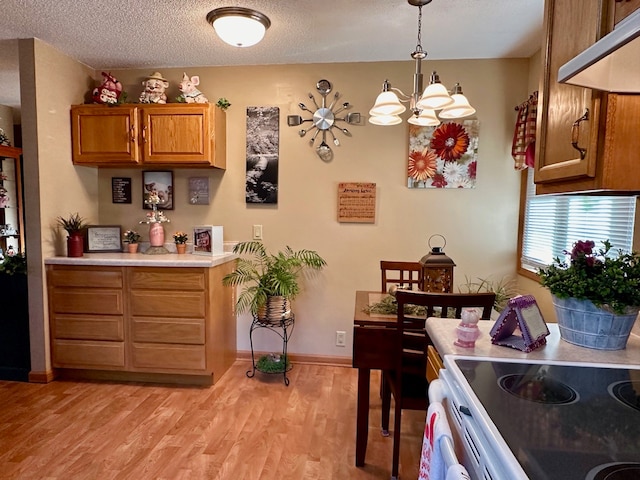 kitchen with white electric range oven, light hardwood / wood-style flooring, a notable chandelier, a textured ceiling, and decorative light fixtures