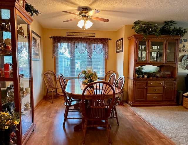 dining space featuring ceiling fan, wood-type flooring, and a textured ceiling