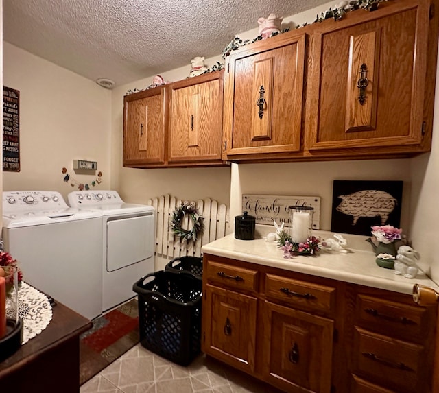 laundry room featuring washer and dryer, light tile patterned floors, cabinets, and a textured ceiling