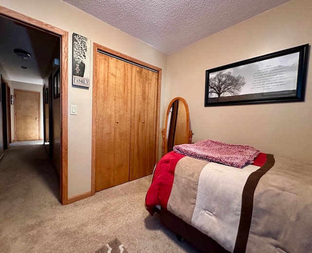 carpeted bedroom with a textured ceiling and a closet