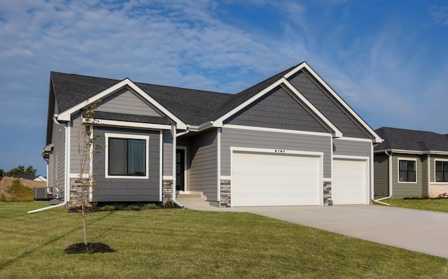 craftsman inspired home with a garage, a front lawn, and central air condition unit