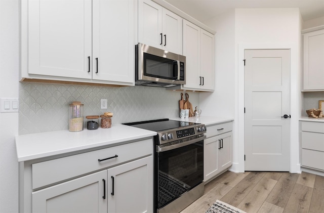 kitchen featuring white cabinets, appliances with stainless steel finishes, backsplash, and light hardwood / wood-style floors