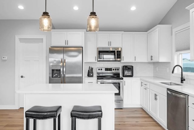 kitchen with white cabinets, decorative light fixtures, a kitchen bar, and stainless steel appliances