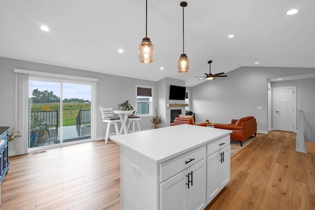 kitchen featuring white cabinetry, a center island, ceiling fan, light hardwood / wood-style floors, and lofted ceiling