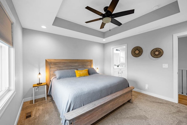 bedroom featuring carpet, ceiling fan, connected bathroom, and a tray ceiling