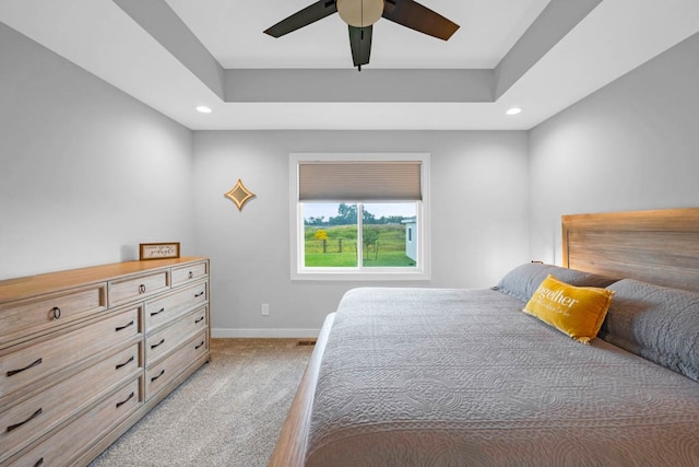 carpeted bedroom with a tray ceiling and ceiling fan