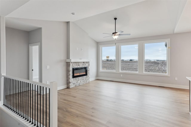 unfurnished living room with a fireplace, light wood-type flooring, vaulted ceiling, and ceiling fan