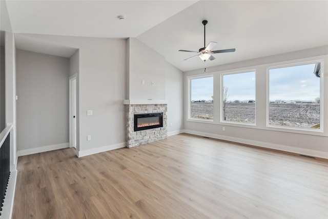 unfurnished living room with ceiling fan, a fireplace, vaulted ceiling, and light hardwood / wood-style flooring